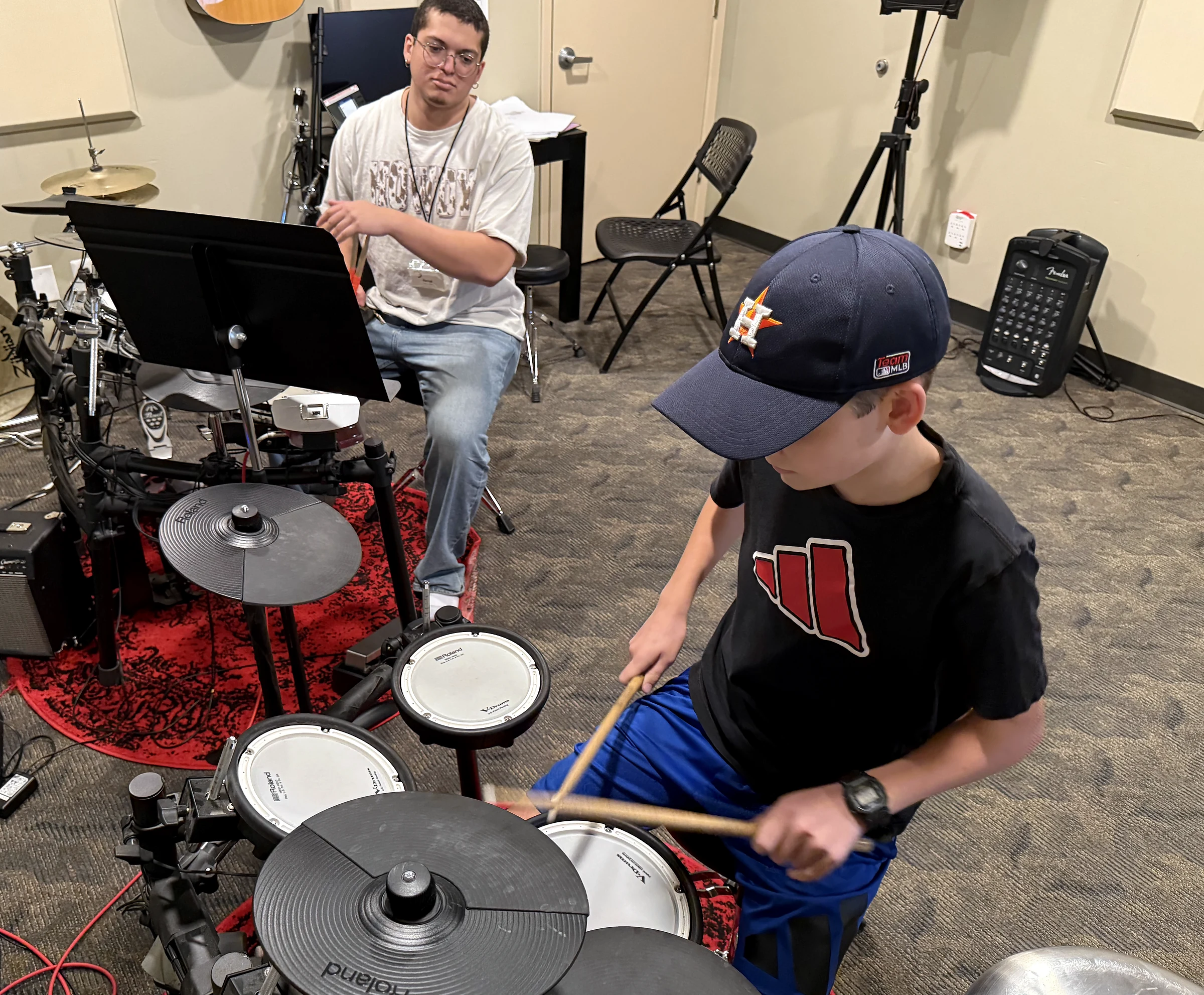 Darrel guides a student playing an electronic drum kit.