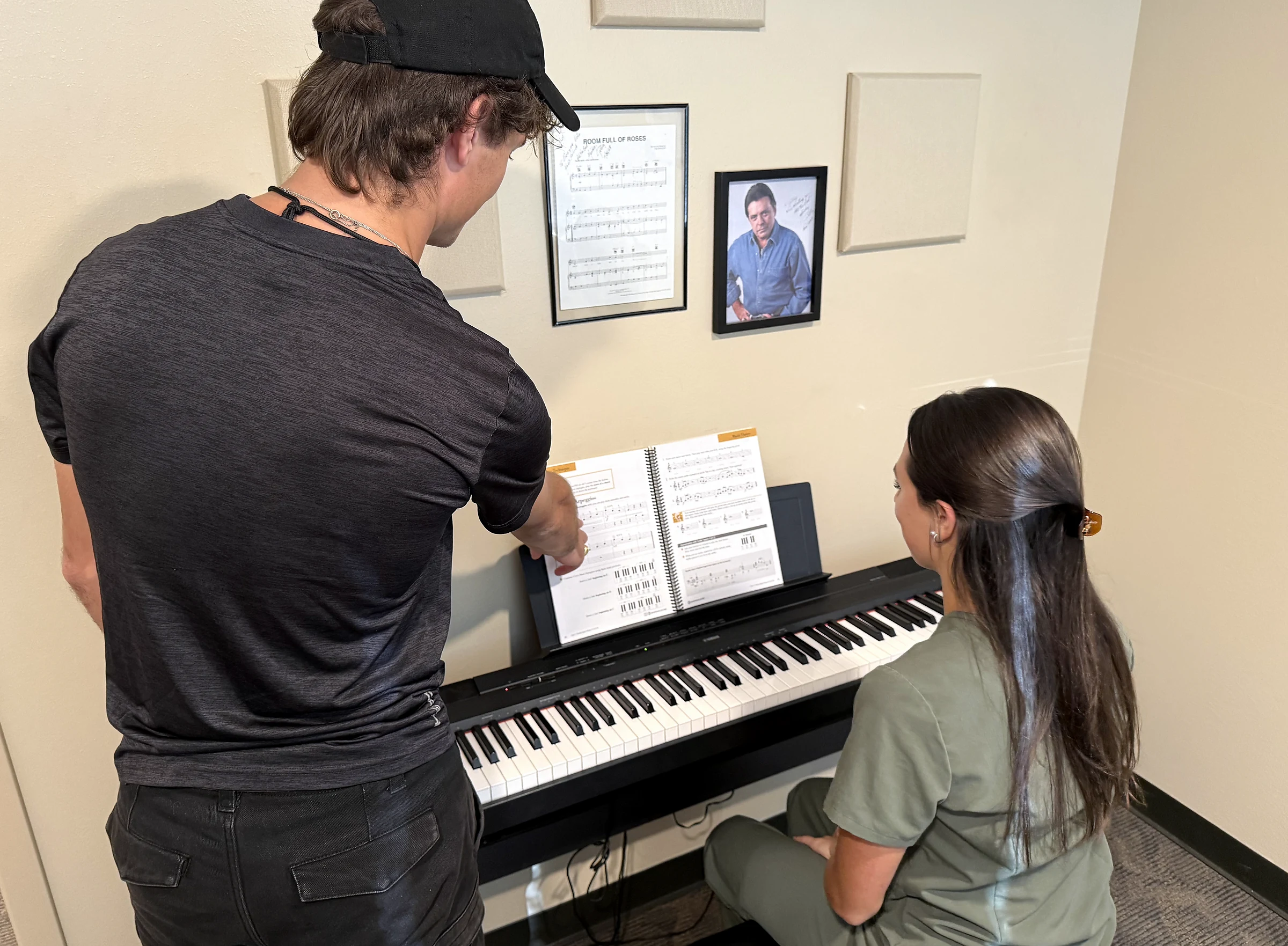 John points to sheet music while a student sits at a piano keyboard.