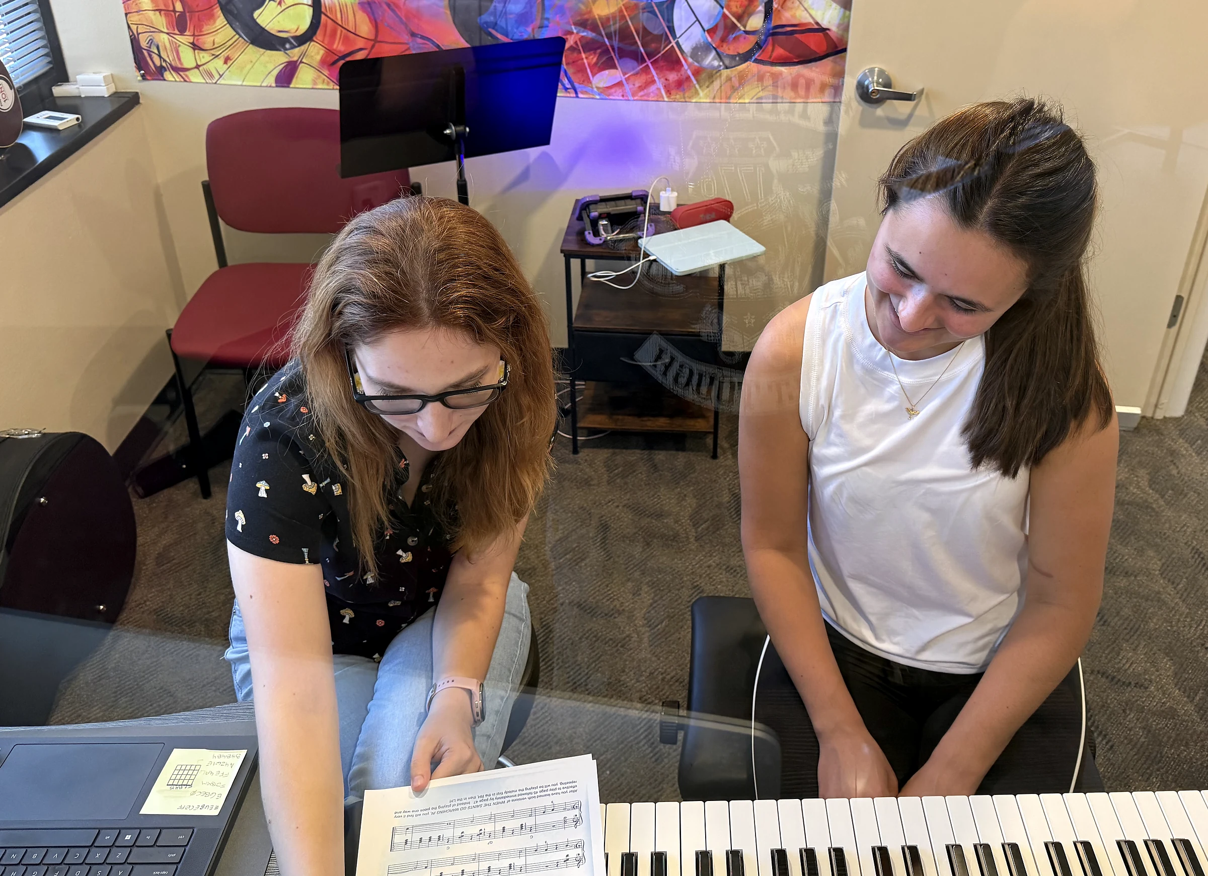Valerie and an adult student review sheet music beside a piano keyboard.