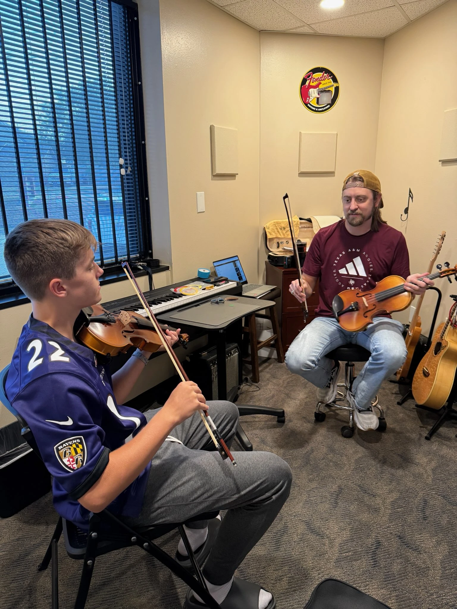 AJ Hoffman guides a student holding a violin and bow during a private lesson at Music Lessons 1on1.